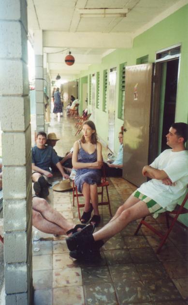 AE_1_29.jpg - Brigadistas sitting in front of a dormitory. Miranda is looking a bit bored because she's trapped and if she tries to escape, she'll fall over a pair of legs.